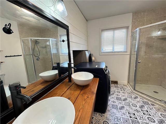 bathroom with a stall shower, washer / clothes dryer, and a sink