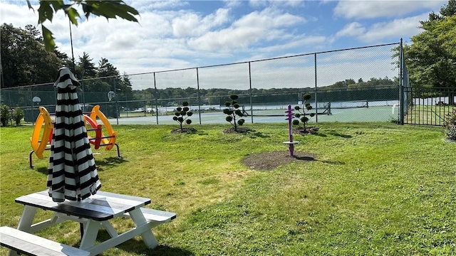 view of home's community with a tennis court, a yard, and fence