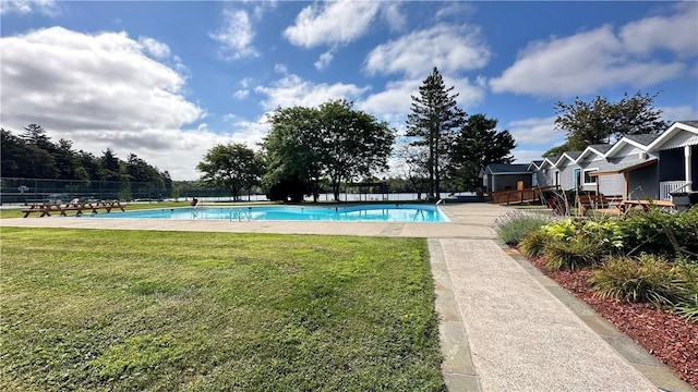 pool with a wooden deck, a lawn, and fence