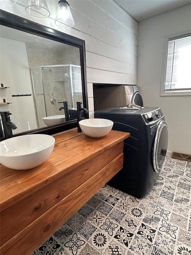 full bath with tile patterned floors, double vanity, a shower stall, and a sink