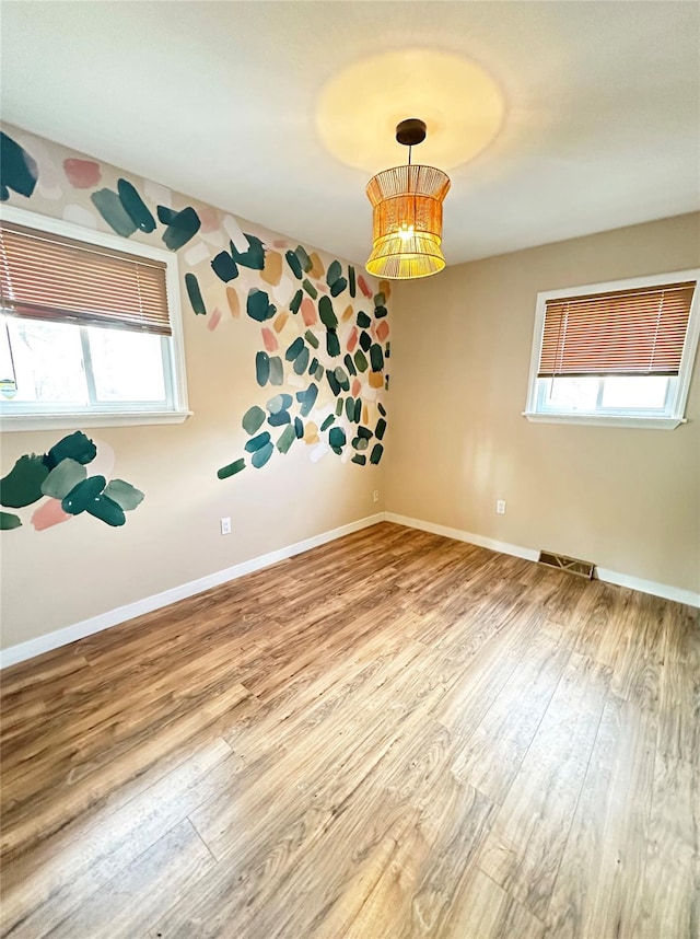 empty room featuring visible vents, baseboards, and wood finished floors