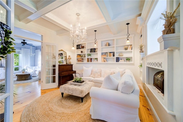 living room featuring coffered ceiling, ceiling fan with notable chandelier, crown molding, light wood-type flooring, and beamed ceiling