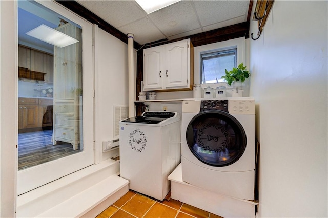 washroom featuring washer and dryer, light tile patterned flooring, and cabinets