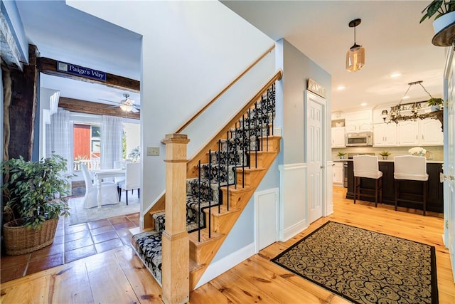 staircase featuring ceiling fan, hardwood / wood-style floors, and beamed ceiling