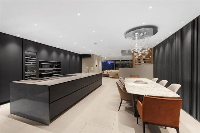 kitchen featuring sink, wall oven, oven, a spacious island, and light tile patterned flooring