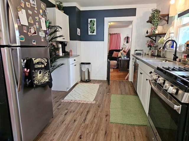 kitchen with light hardwood / wood-style floors, white cabinetry, sink, and appliances with stainless steel finishes