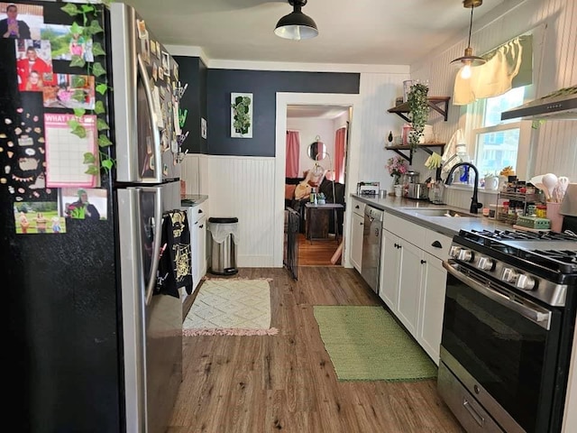 kitchen featuring appliances with stainless steel finishes, sink, decorative light fixtures, hardwood / wood-style flooring, and white cabinets