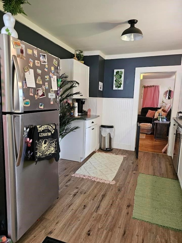 kitchen with stainless steel refrigerator, crown molding, hardwood / wood-style floors, and white cabinets