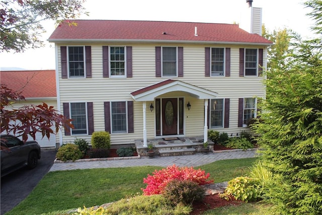 colonial-style house featuring a front lawn