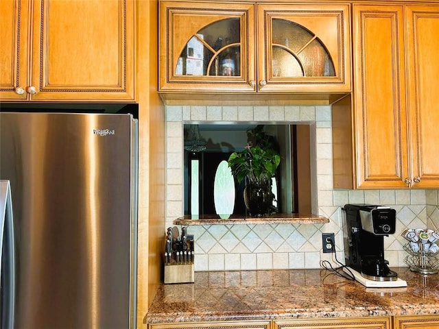 kitchen with stainless steel fridge, backsplash, and stone countertops