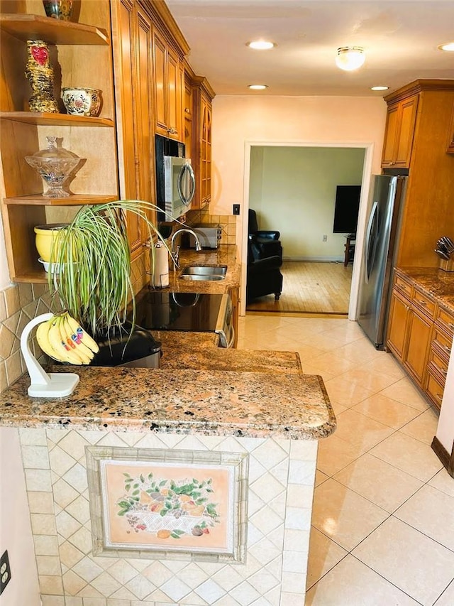 kitchen with light tile patterned flooring, light stone counters, sink, and appliances with stainless steel finishes