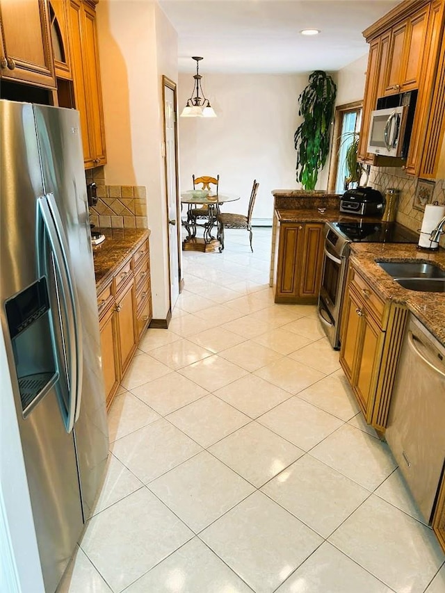 kitchen featuring appliances with stainless steel finishes, tasteful backsplash, sink, hanging light fixtures, and light tile patterned flooring