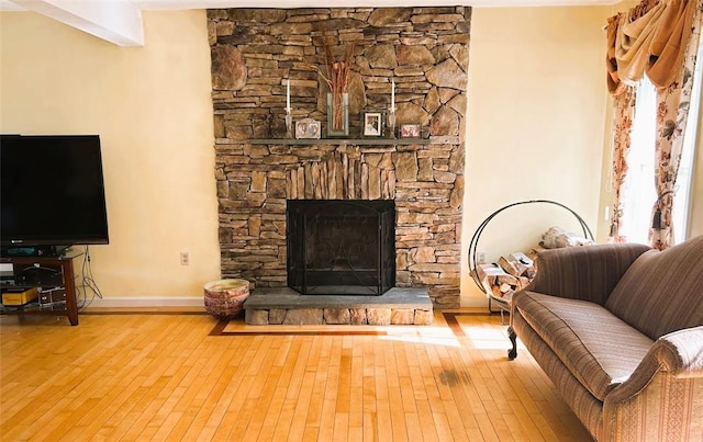 living room with a stone fireplace and light wood-type flooring