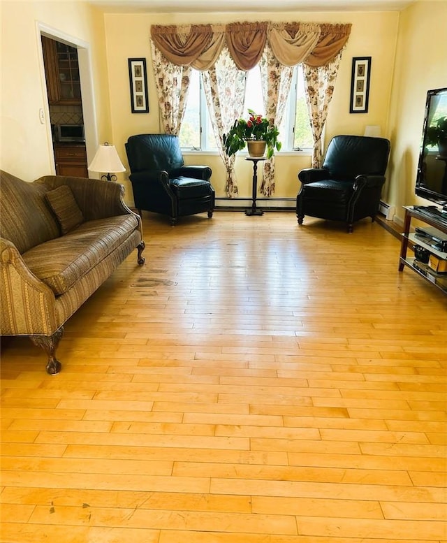 living room with a baseboard heating unit and light wood-type flooring