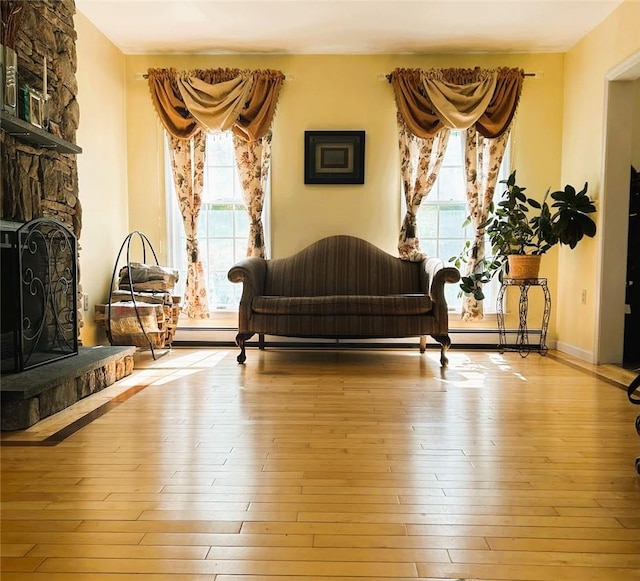 living area featuring light wood-type flooring and a stone fireplace