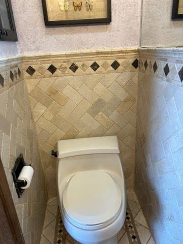 bathroom with tile patterned flooring, toilet, and tile walls