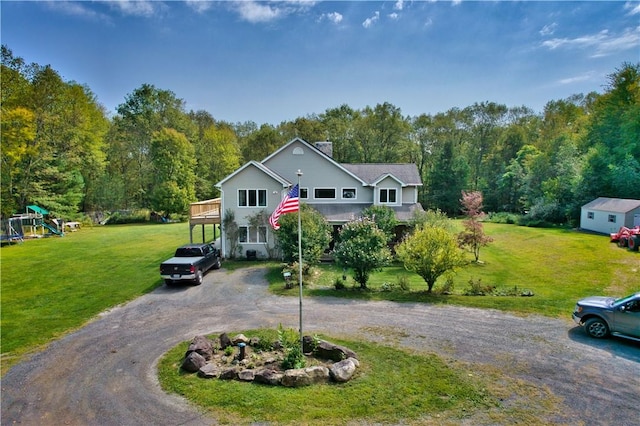 view of front of house with a deck, a playground, and a front lawn