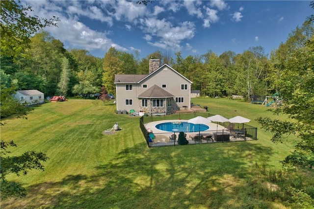 rear view of property with a yard and a fenced in pool