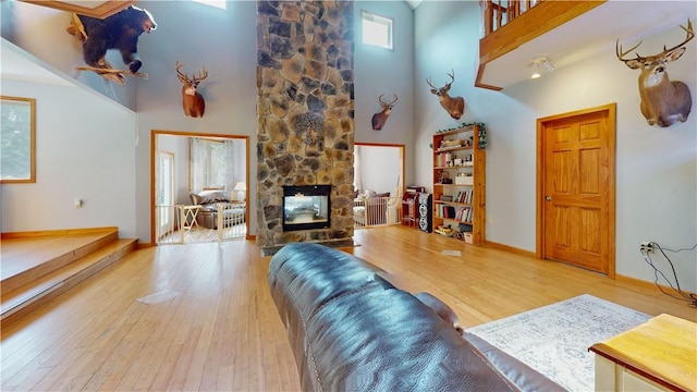 living room featuring light wood-type flooring, a fireplace, and a high ceiling