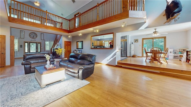 living room with a high ceiling, ceiling fan, and wood-type flooring