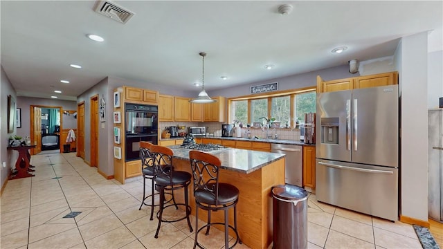 kitchen featuring stainless steel appliances, a kitchen island, tasteful backsplash, decorative light fixtures, and light tile patterned floors