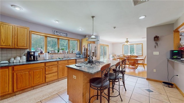 kitchen featuring ceiling fan, a kitchen island, a healthy amount of sunlight, and appliances with stainless steel finishes