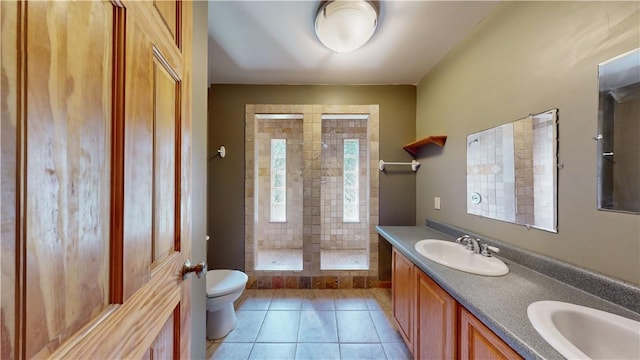 bathroom featuring vanity, tile patterned floors, toilet, plenty of natural light, and a tile shower