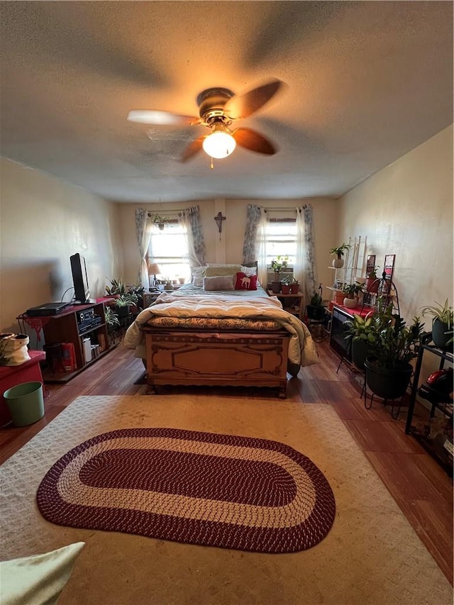 bedroom featuring hardwood / wood-style floors, ceiling fan, a textured ceiling, and multiple windows