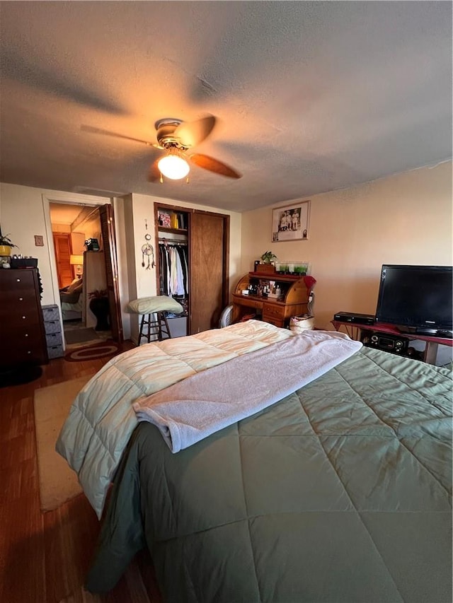 bedroom with ceiling fan, a closet, wood-type flooring, and a textured ceiling