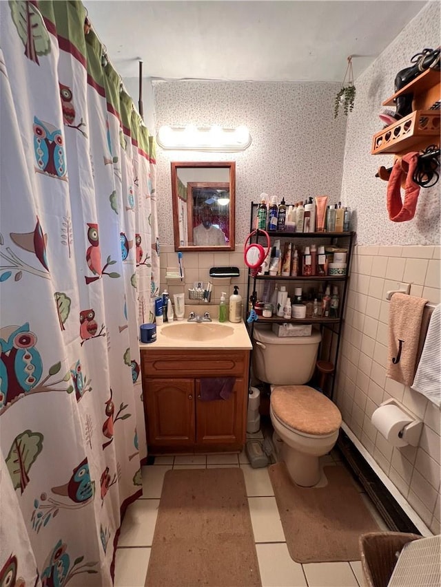 bathroom featuring toilet, vanity, tile patterned floors, and tile walls