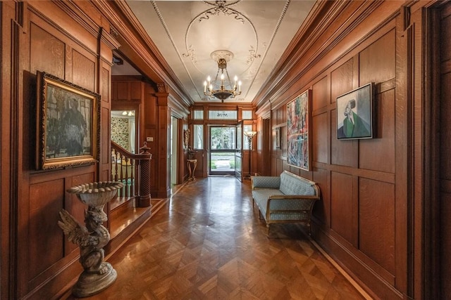 foyer featuring a chandelier, dark parquet floors, wooden walls, and crown molding