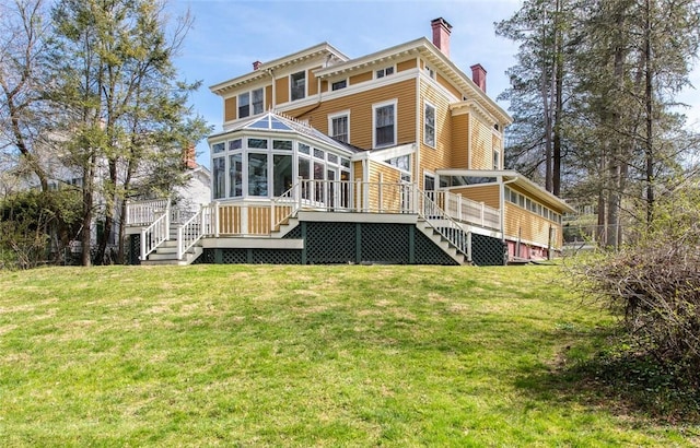 back of house with a wooden deck, a lawn, and a sunroom