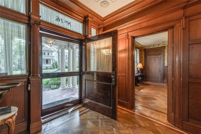 doorway to outside featuring crown molding, plenty of natural light, and parquet flooring