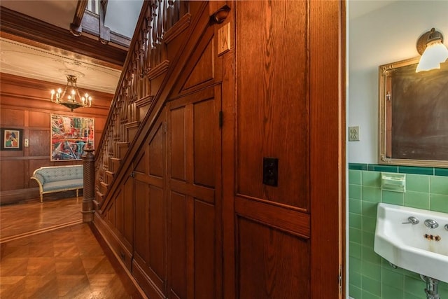 corridor with dark parquet floors, an inviting chandelier, and sink