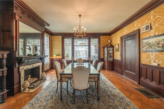 dining area featuring a chandelier, light parquet floors, a fireplace, and ornamental molding