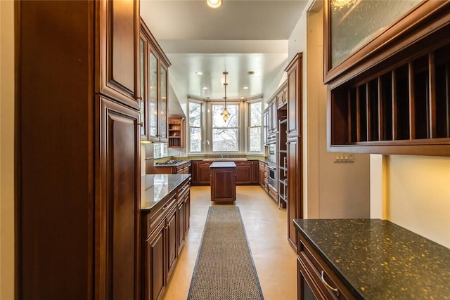 kitchen featuring oven, decorative light fixtures, and dark stone counters