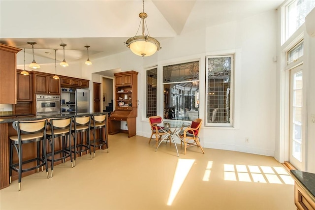 kitchen featuring a breakfast bar area, pendant lighting, stainless steel appliances, and vaulted ceiling