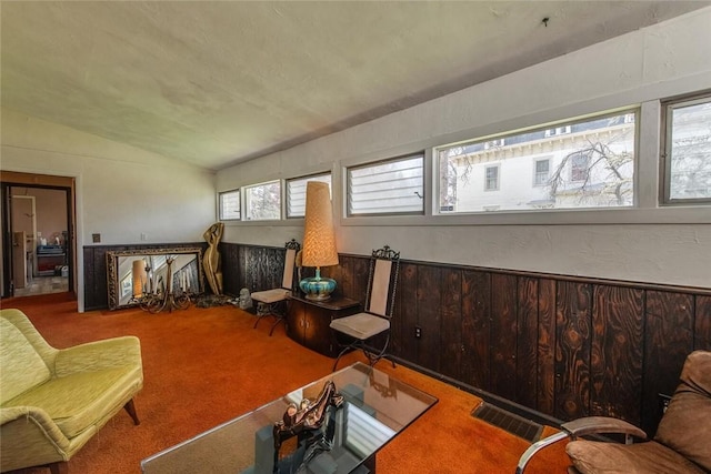 carpeted living room with wood walls and lofted ceiling