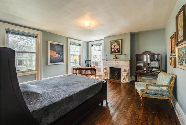 bedroom featuring dark hardwood / wood-style floors, a brick fireplace, and multiple windows