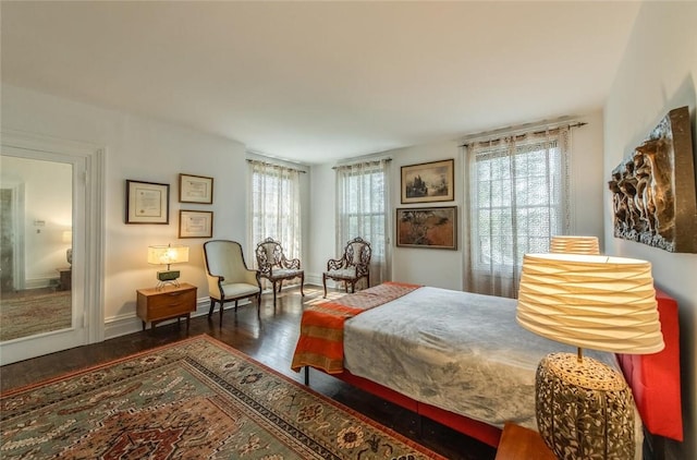 bedroom with multiple windows and dark wood-type flooring