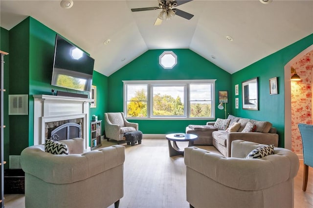 living room featuring a fireplace, ceiling fan, light hardwood / wood-style flooring, and vaulted ceiling