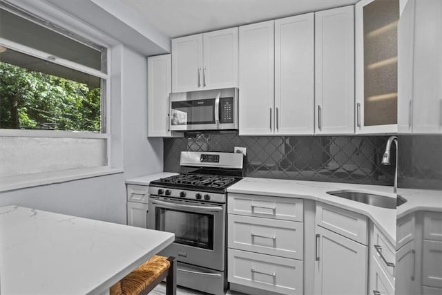 2575 Palisade Ave Unit 2J, Bronx, NY 10463 - kitchen featuring stainless steel appliances, a sink, white cabinets, decorative backsplash, and glass insert cabinets