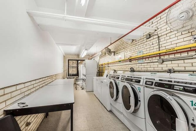 laundry room with washer and dryer and brick wall