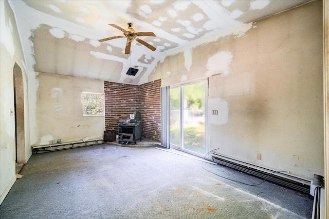 unfurnished living room featuring a wood stove, baseboard heating, lofted ceiling, and ceiling fan