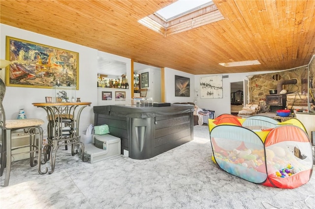 living room featuring wooden ceiling, a wood stove, and a skylight