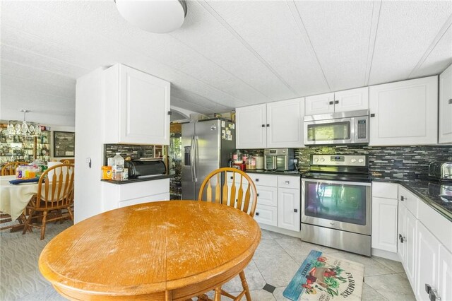 kitchen with decorative backsplash, white cabinetry, light tile patterned floors, and appliances with stainless steel finishes