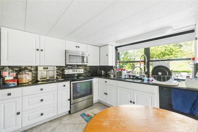 kitchen featuring decorative backsplash, light tile patterned floors, a textured ceiling, appliances with stainless steel finishes, and white cabinetry