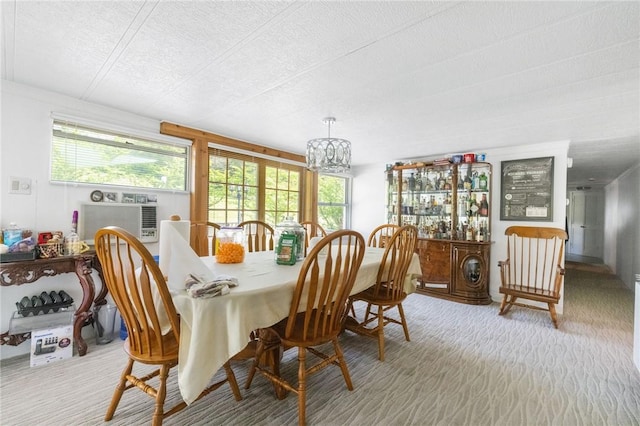 carpeted dining room featuring cooling unit, a textured ceiling, and a notable chandelier