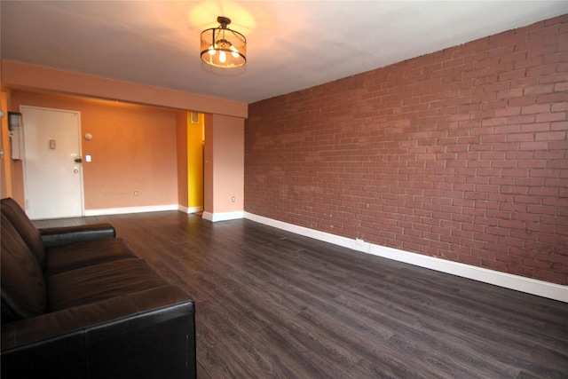 unfurnished living room with brick wall and dark hardwood / wood-style floors