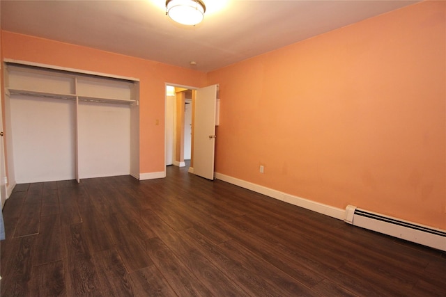 unfurnished bedroom with a baseboard heating unit, a closet, and dark wood-type flooring